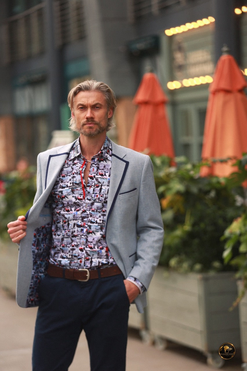 A model wears a Claudio Lugli Monaco Grand Prix print shirt under a tailored blazer on a Riviera-style street
