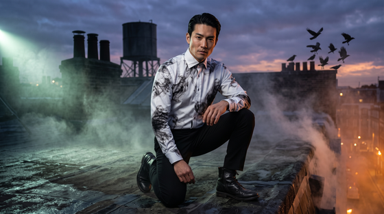 Smoke print shirt men: Japanese man early 30s crouched low looking up at the lens on a foggy London rooftop at dusk, crows and green key light, Claudio Lugli Smoke Print Shirt buttoned to the collar, black trousers and boots