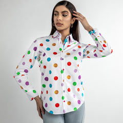 Woman wearing a vibrant multicolour polkadot print shirt styled with light wash jeans.