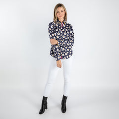 Woman wearing navy daisy flower print shirt with white pants and black boots.