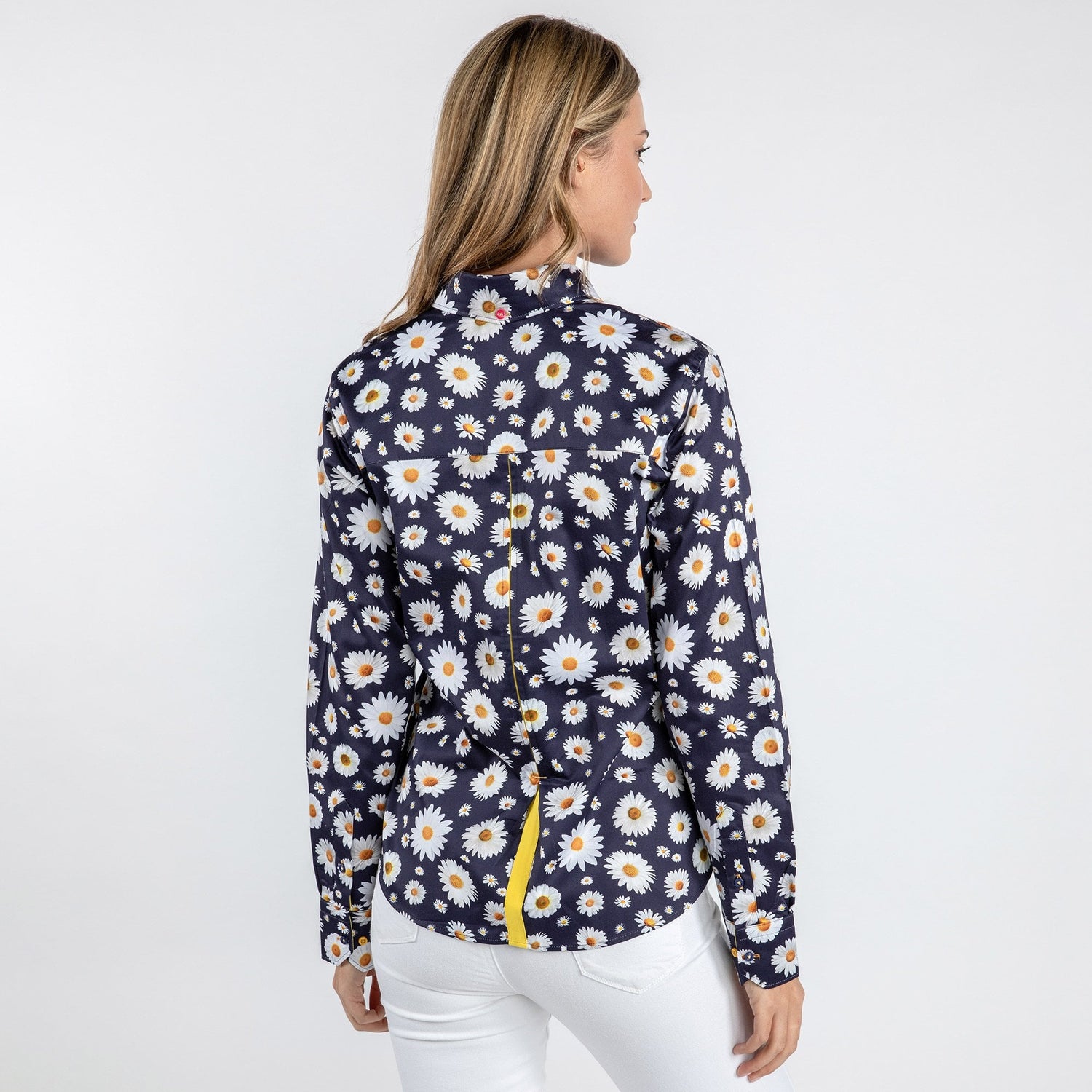 Woman wearing navy daisy flower print women's shirt with long sleeves and white pants, back view