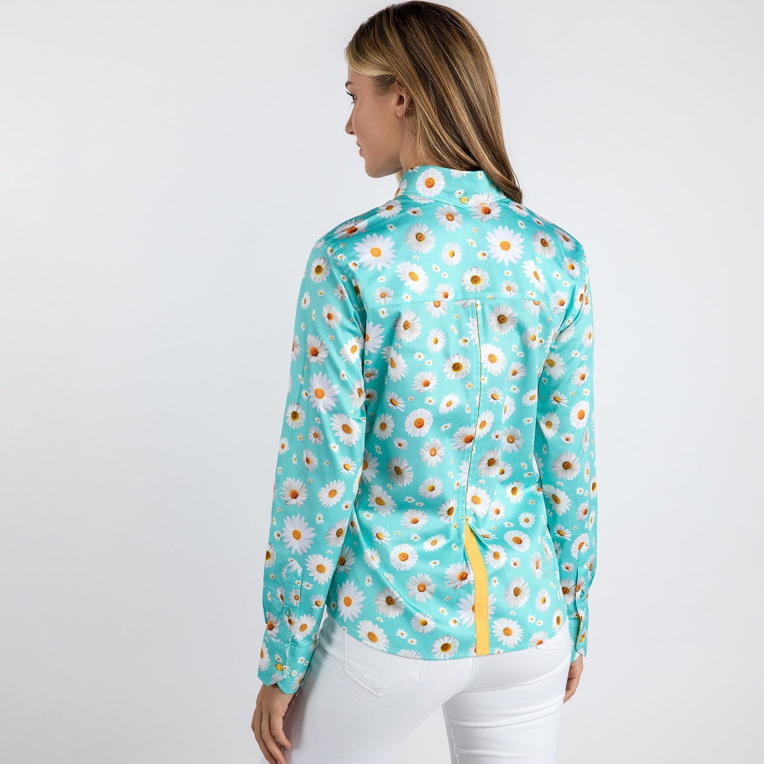 Woman wearing a sky blue daisy flower print shirt with white pants, showcasing the back view.