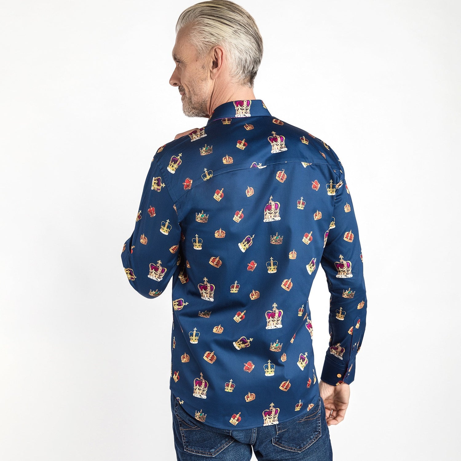 Man wearing THE CROWN Regal Print Shirt by Claudio Lugli with intricate crown motifs, fuchsia inserts, and multicolored buttons.