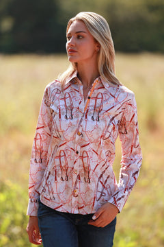 Woman wearing SNAFFLE WOMEN PRINT SHIRT with equestrian snaffle design in countryside setting.