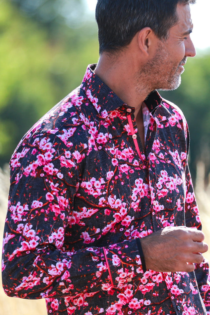 Claudio Lugli Plum Blossom shirt close-up on a model, showing vivid pink flowers on a dark ground, a contrasting inner collar and buttoned cuff